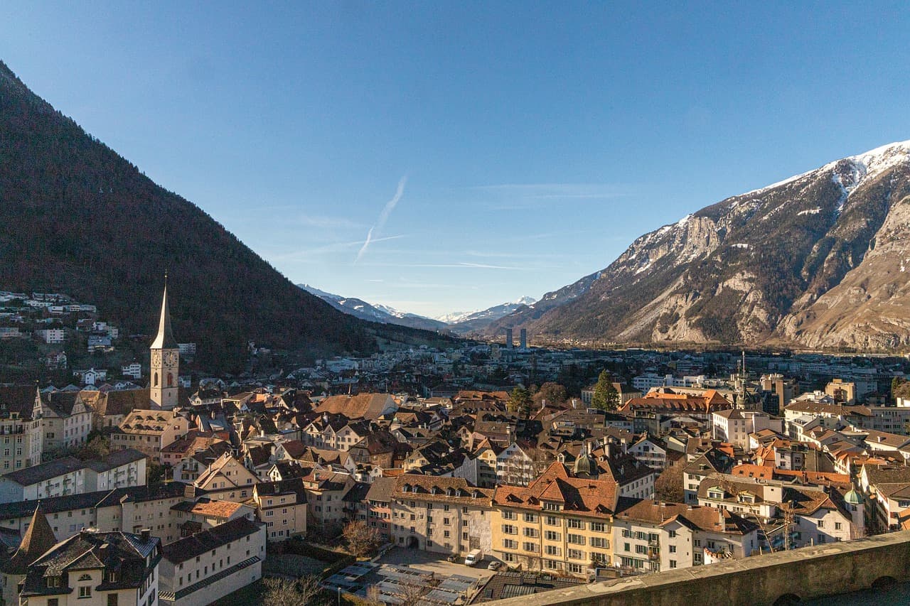 Panoramablick über die Altstadt von Chur mit historischen Häusern und Kirchturm vor den Alpen im Kanton Graubünden in der Schweiz.